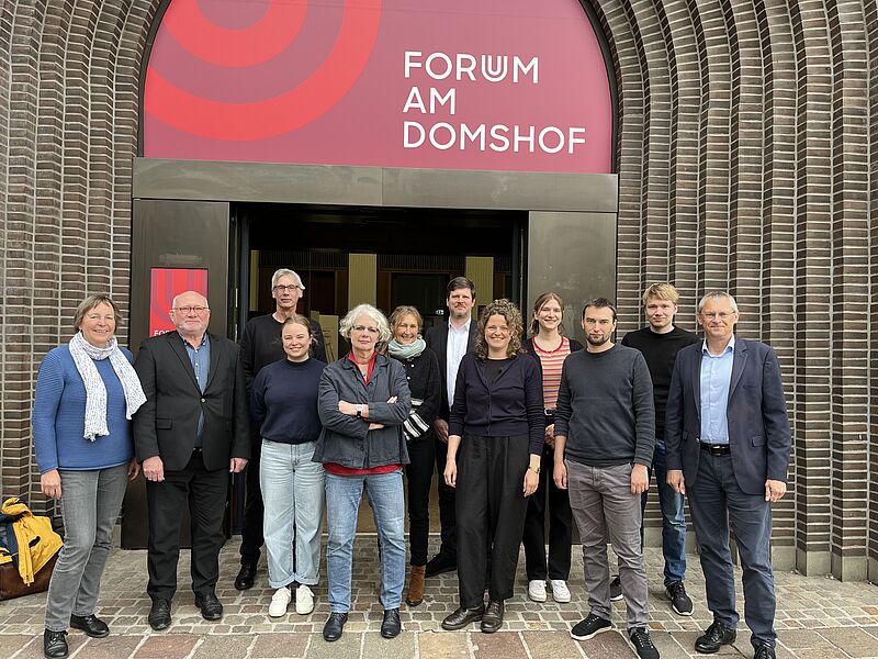 Gruppenbild (12 Personen) des Projektonsortiums vor der Tür zum Forum am Domshof