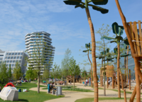 credit: ELBE&FLUT / Thomas Hampel; Ein Bild vom Grasbrookpark - ein Spielplatz, umliegende Hochhäuser, Grünflächen, spielende Kinder, sitzende und gehende Menschen